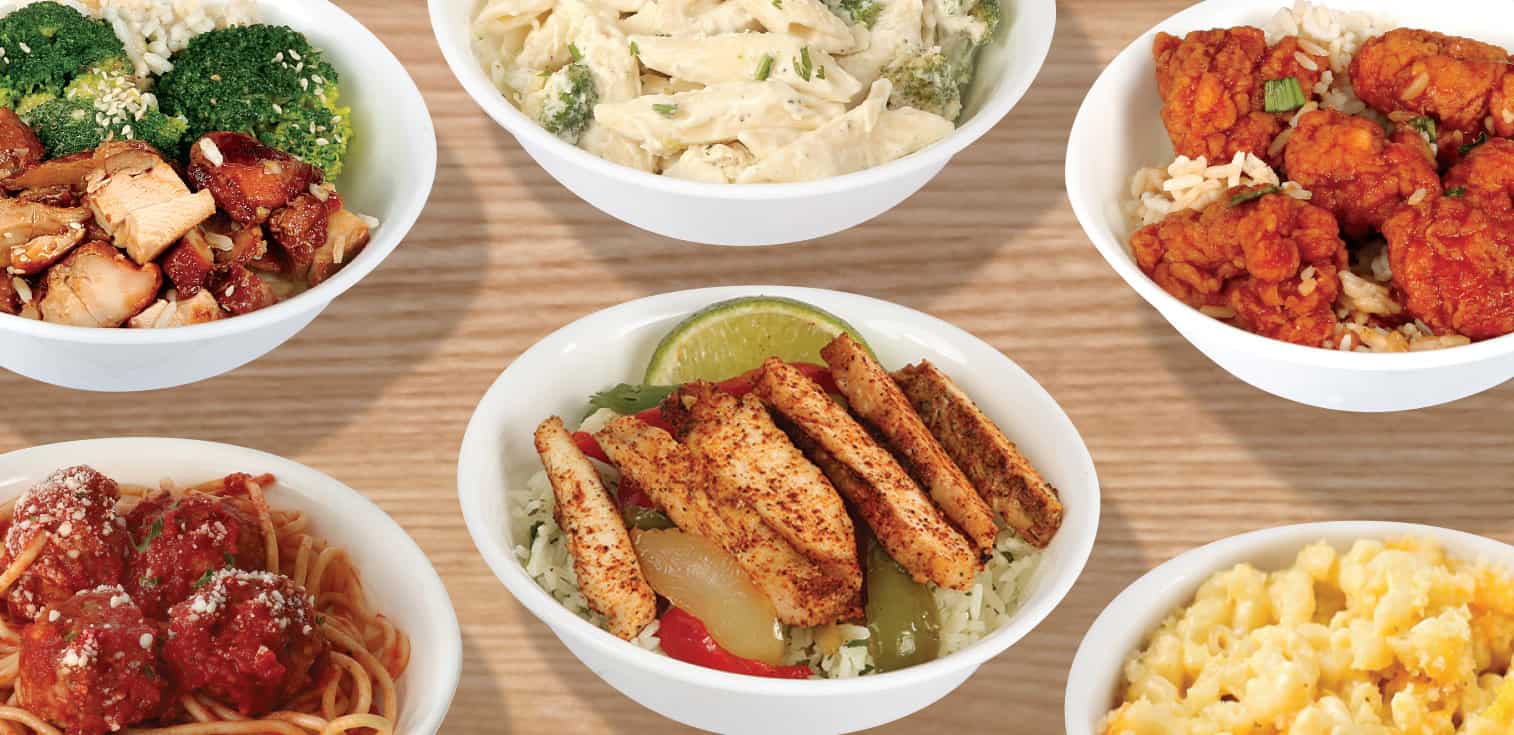 Six white bowls on a light wood background showcasing various meals: spaghetti with meatballs, seasoned chicken with peppers and rice, creamy pasta with broccoli, orange chicken over rice, and macaroni and cheese.